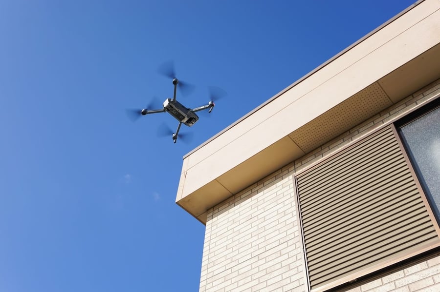 都市部のビル風を警戒しながら建物の近くを飛行するドローンの様子