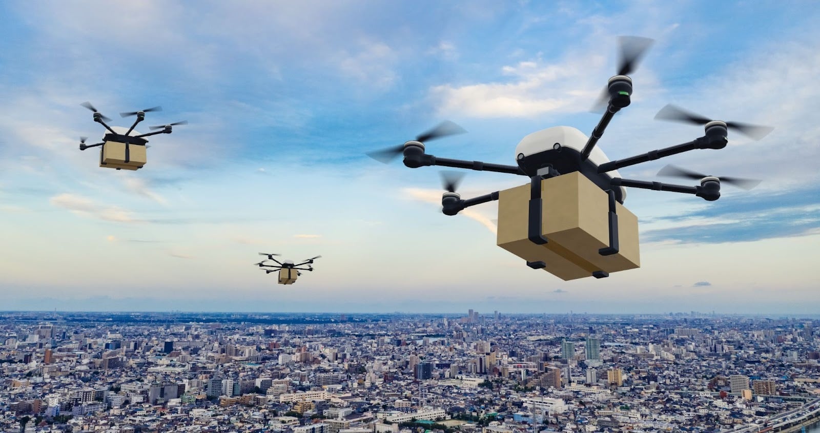 荷物を運んで市街地の上空を飛ぶドローンのイメージ